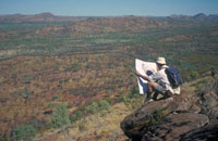 A geologists compares terrain with a map of the area. (© Geoscience Australia)