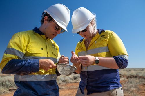 Two geoscientists, one male, one female - wearing yellow high visibility shirts