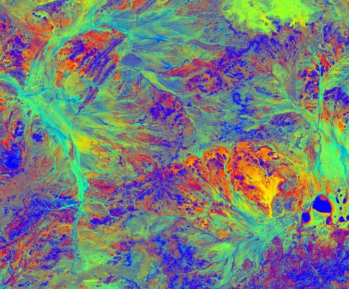 fluorescent pink, blue, purple, and yellow abstract image of complex landscape as captured by satellite