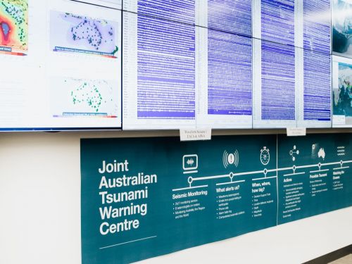 The JATW alert system protocol poster sits underneath the wall monitors that display seismic activity across Australia in the National Earthquake Alert Centre room.