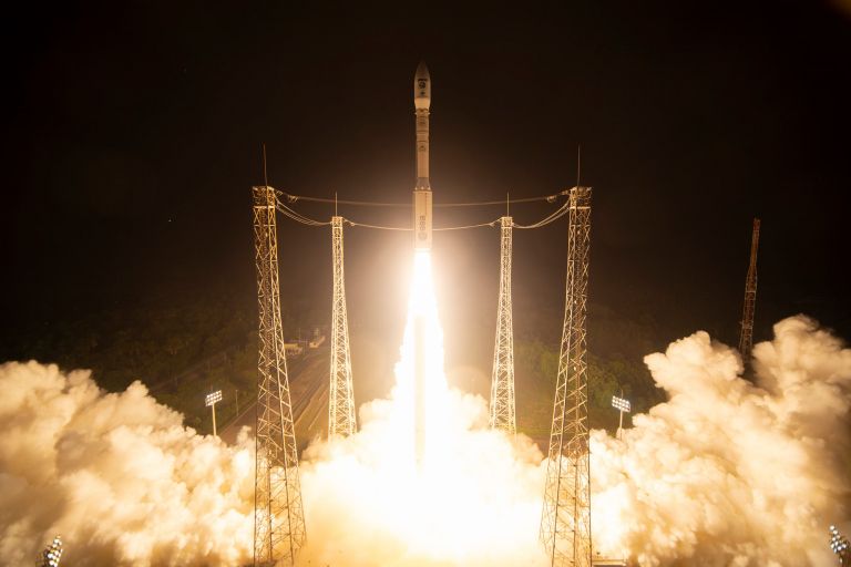 A rocket taking off with a trail of flames and surrounded by a plumb of smoke.