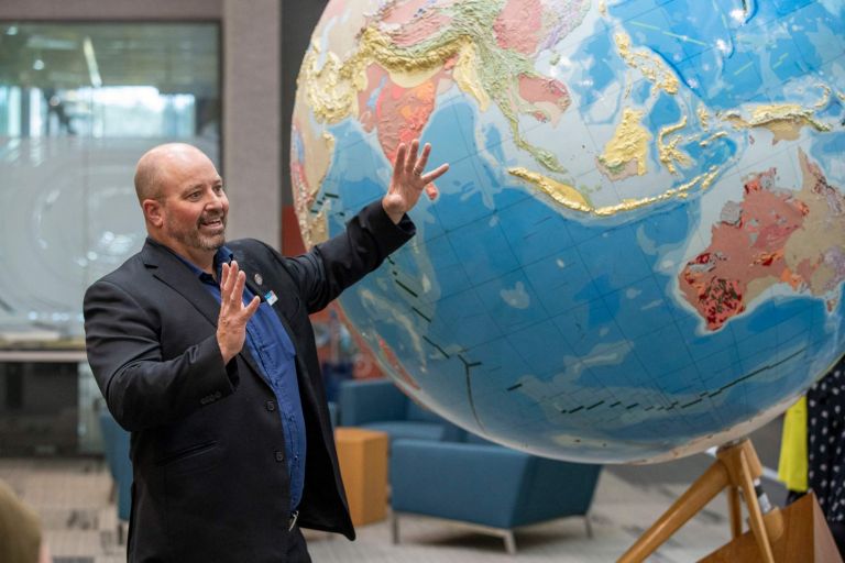 man standing in front of large globe