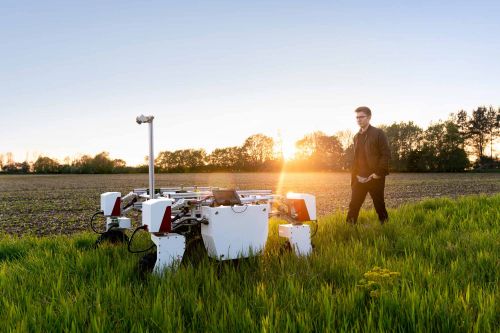 Man controls an electronic crop-walking machine in a field