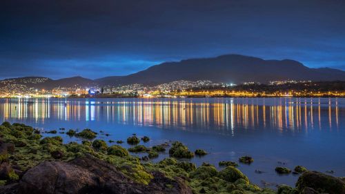 Coastal bay at night with lights from town reflecting on water