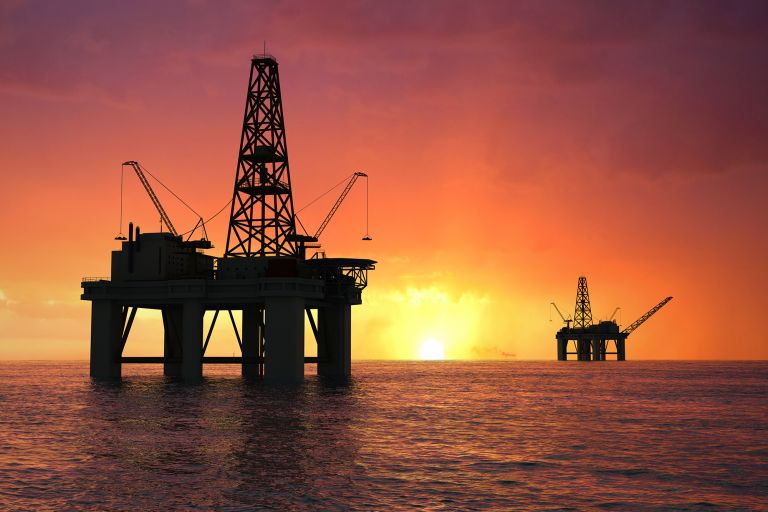 Oil rig silhouette over orange sky